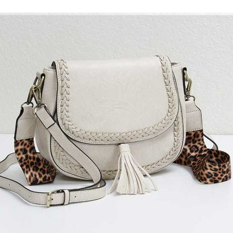 Distressed Buffalo Vegan Saddle bag with whip stitching details  on the handbag. Tassel, magnetic closure  and two straps one coordinating and the other leopard.
